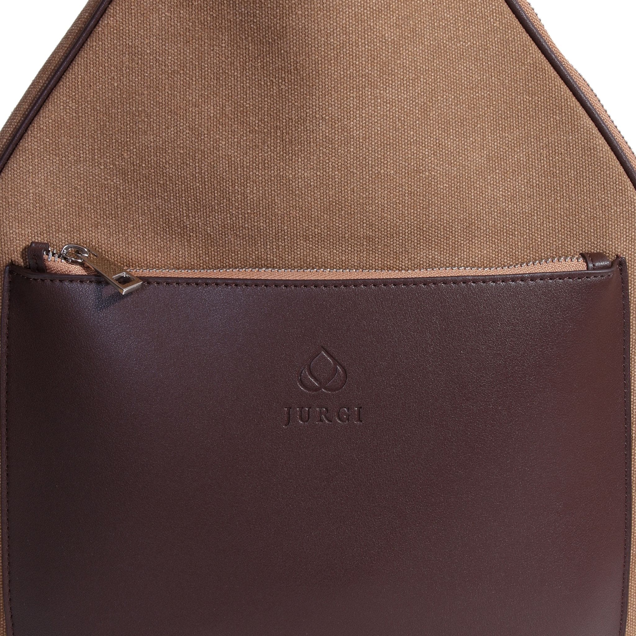 Close-up of a leather tennis bag with a brown fabric body and a darker brown leather front pocket, featuring a zipper and the brand name JURGI embossed below a small logo.