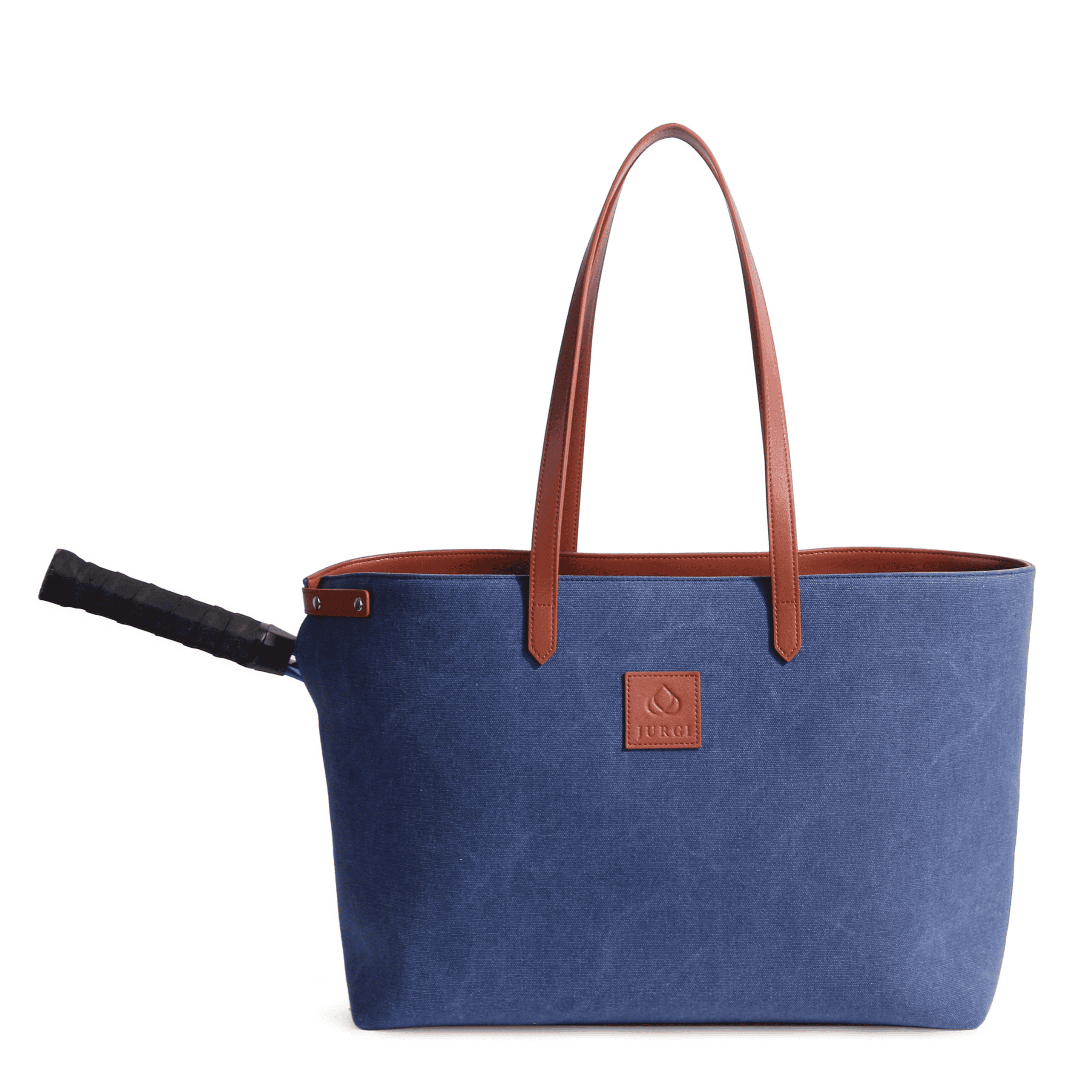 A large blue canvas leather court bag with brown leather handles and a brown logo patch on the front, designed with a side slot perfectly holding a black-handled tennis racket.