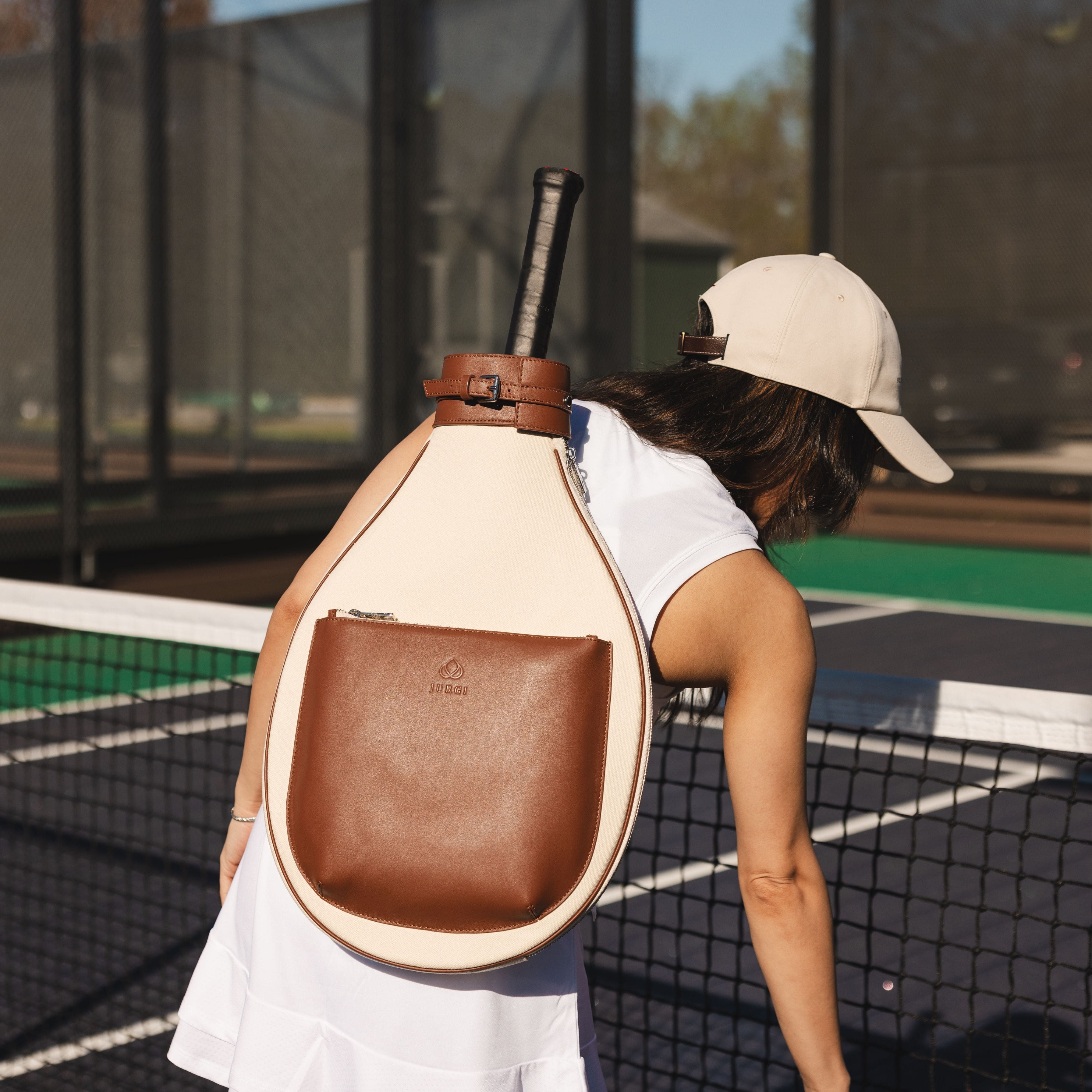 Person on a tennis court wearing a unique backpack with a paddle design.