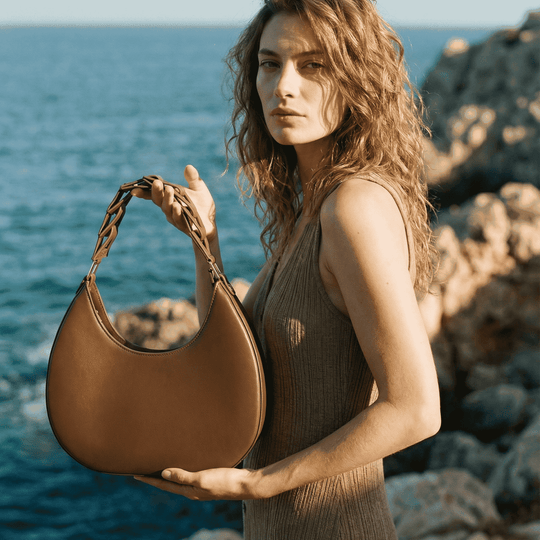 Woman holding a brown leather handbag by the ocean