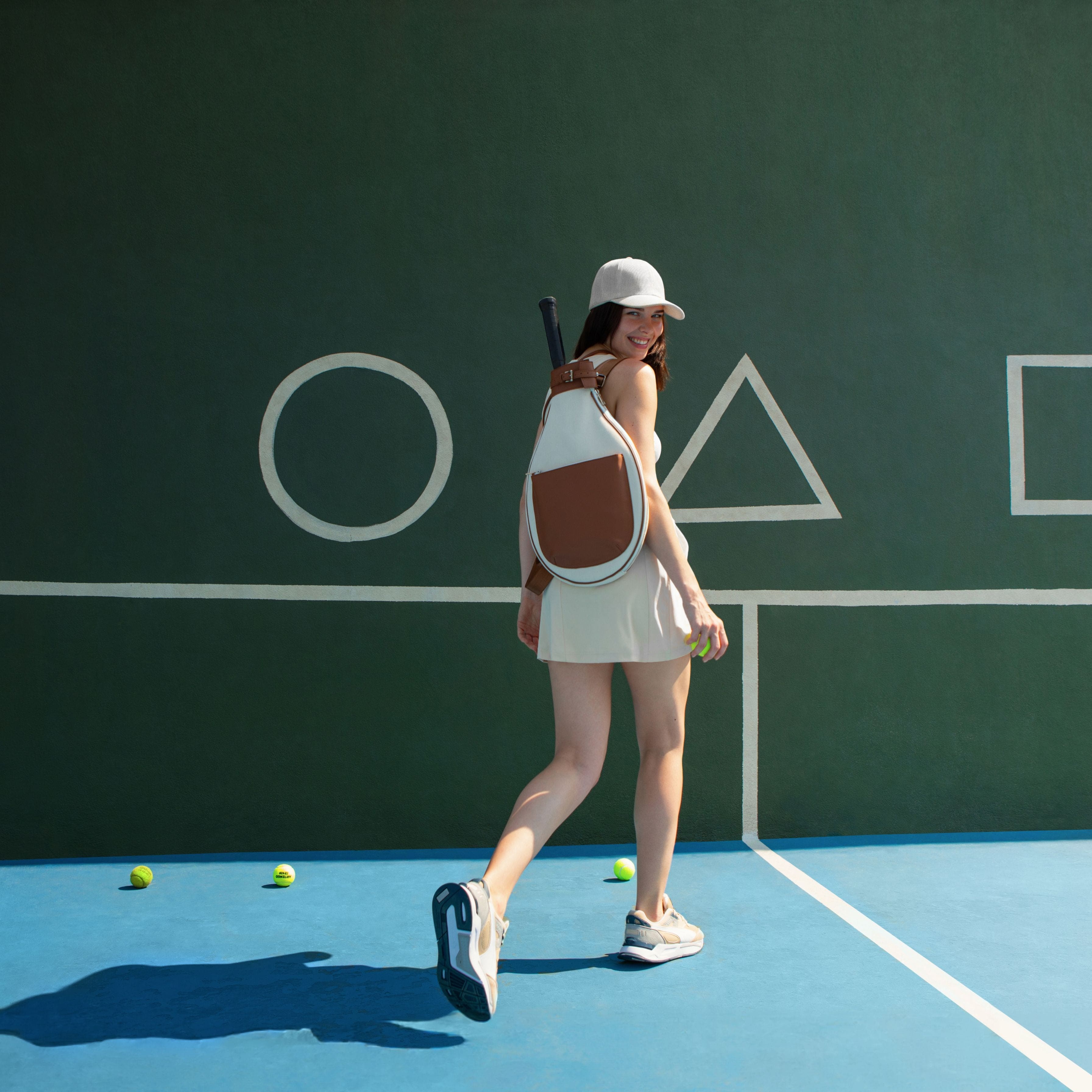 Woman with a tennis racket and backpack on a tennis court