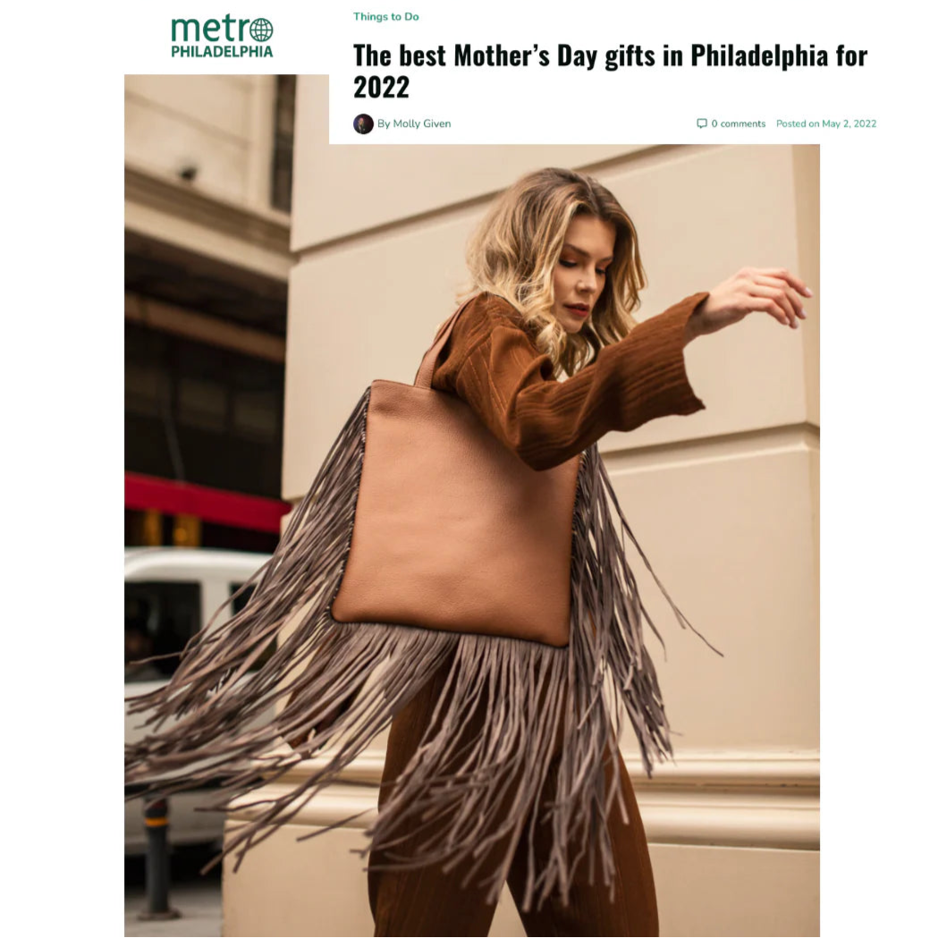 Woman holding a large brown tote bag with fringe details, with 'metro Philadelphia' branding at the top.