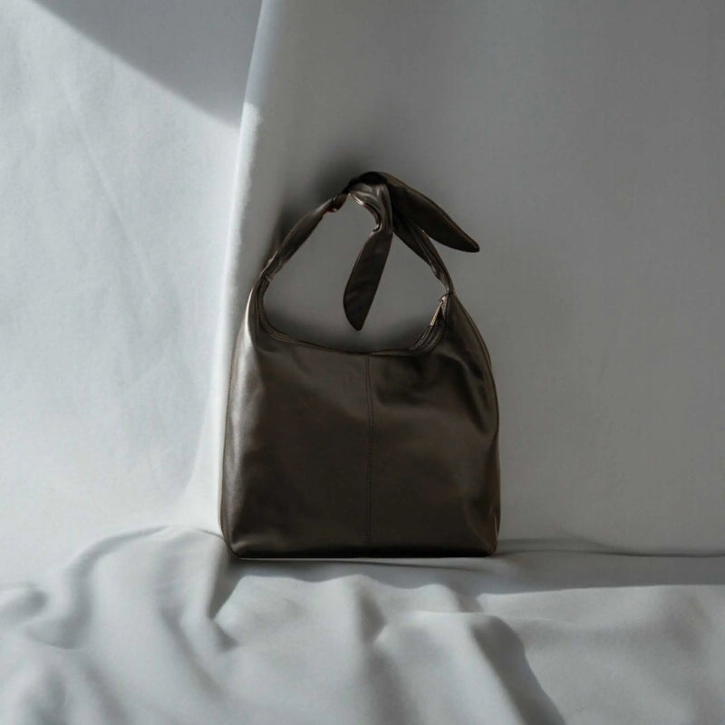 Elegant black suede and leather handbag featuring signature knot strap