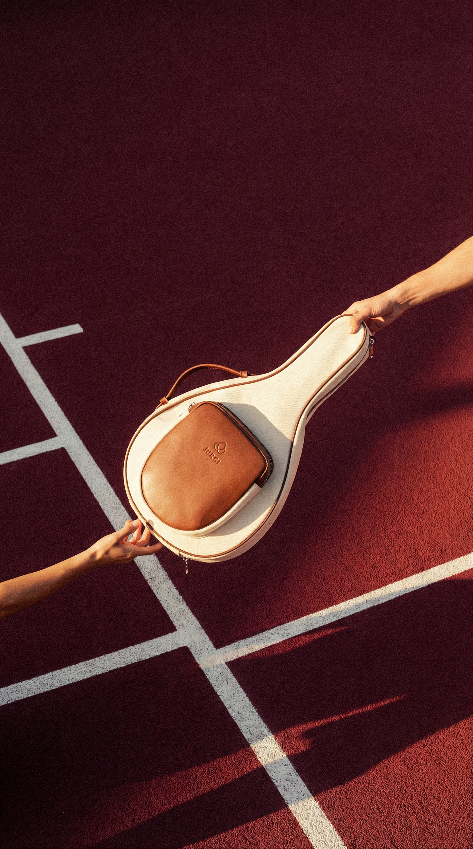 Two hands exchanging a brown leather padel bag on a red-and-white checkered surface.