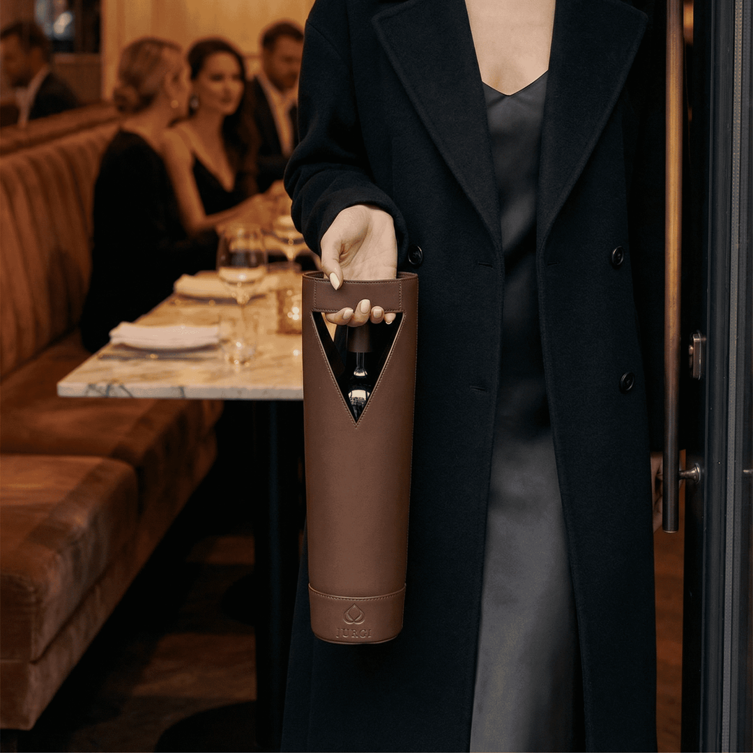 Person holding a brown wine bottle holder in a restaurant setting