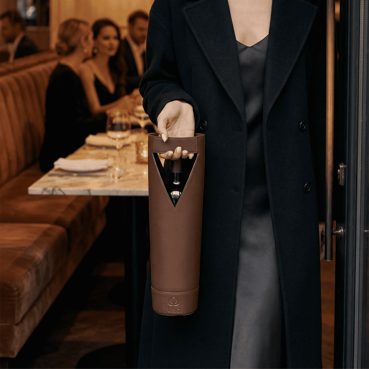 Person holding a brown wine bottle holder in a restaurant setting