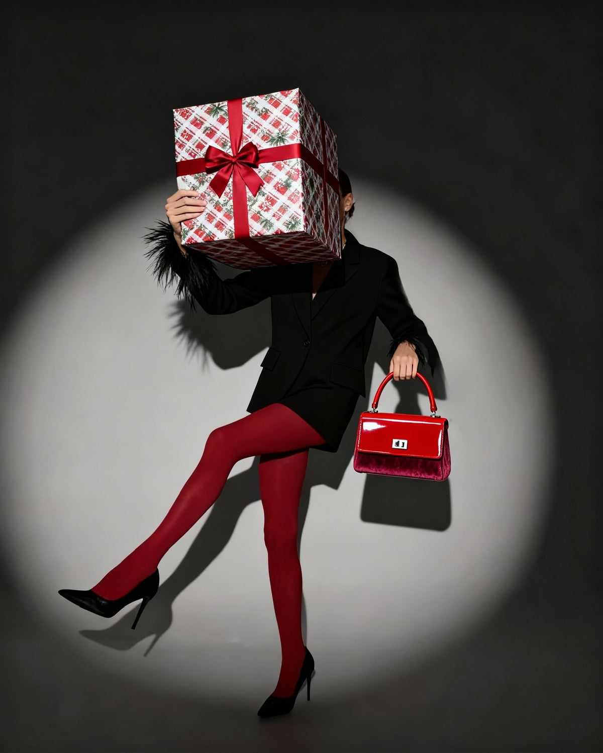 Person holding a large gift box over their head with a red handbag in another hand, on a dark background.