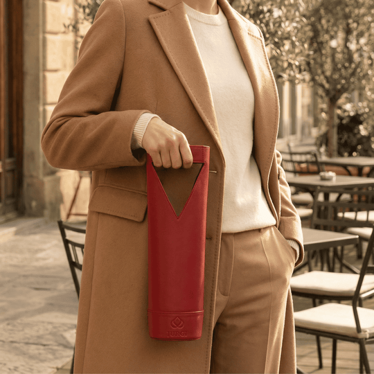Person holding a red thermos in an outdoor setting