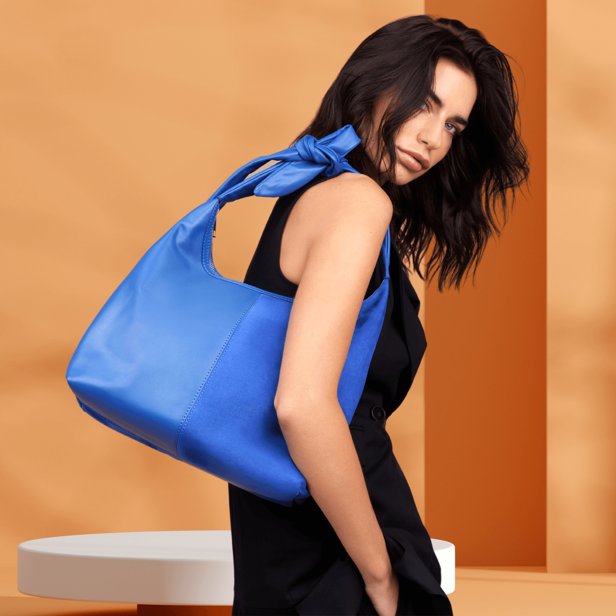 Adjustable knot strap tote with leather and zipper.